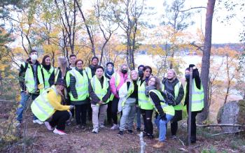Haaga Helia students smiling for the camera in yellow vests in nature. 