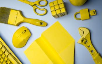 keltaisia työkaluja, lennokki, hiiri, rubikin kuutio, lukko ja näppäimistö.