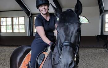 Tutkija Tiina Brandt ratsastamassa mustalla hevosella