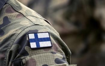 Suomen armeijan sotilaspuku, jossa olkapäässä on Suomen lippu.