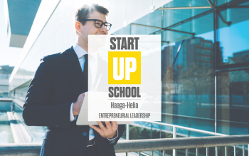 Mies siisti puku päällä ulkona. Päällä StartUp School -logo ja teksti "Entrepreneurial leadership".